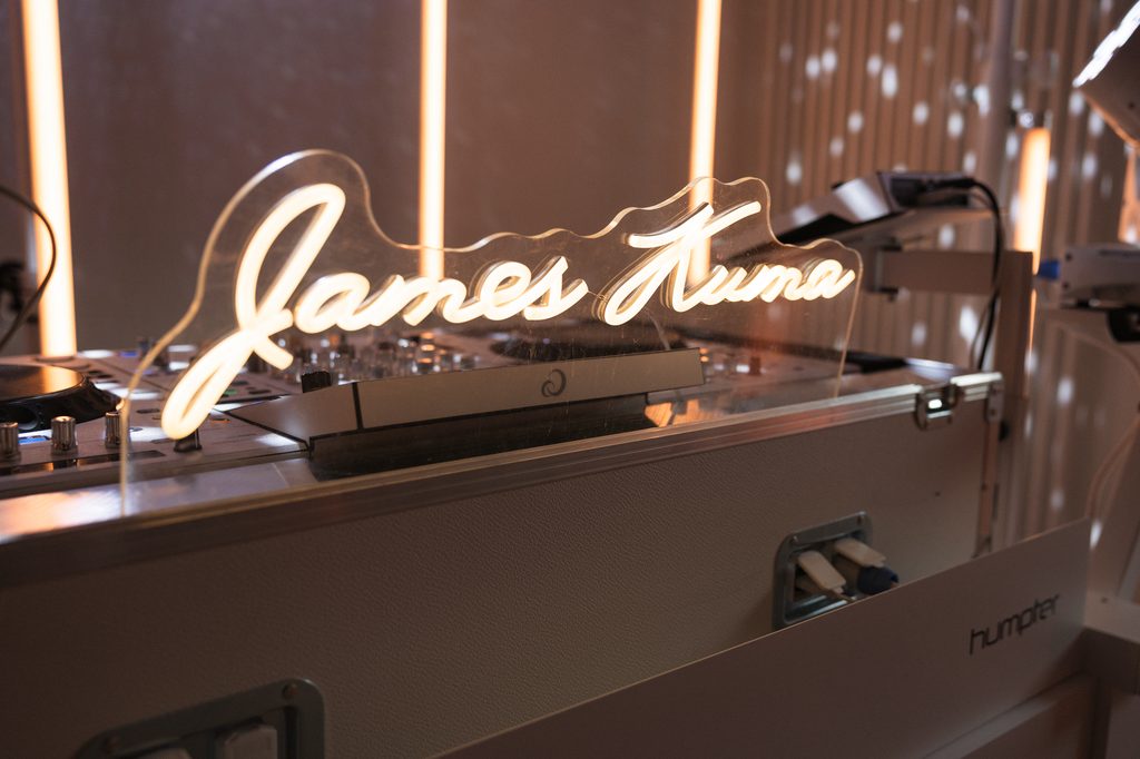 Leuchtender Neon-Schriftzug James Kuma auf der weißen Booth